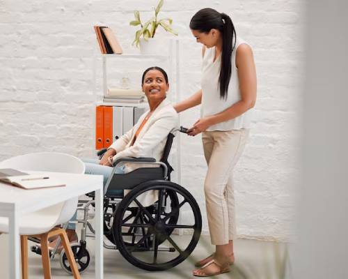 A person in a wheelchair confidently navigating a new workplace with guidance from their Disability Employment Support team